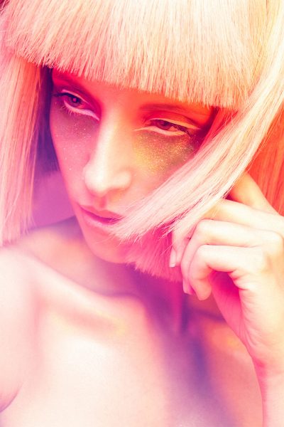 Frau mit hartem Pagenschnitt und knalligem Make-up in Rot-Magenta-Orange