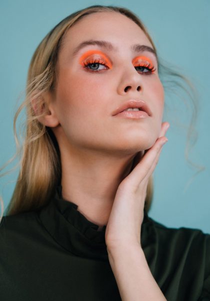 Blonde, junge Frau schaut in Kamera, auffällig orange geschminkte Augen inspiriert von internationalen Make-up Artists