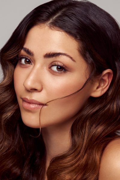 Gesicht einer brünetten Frau mit welligen Haaren und natürlichem Beautymakeup